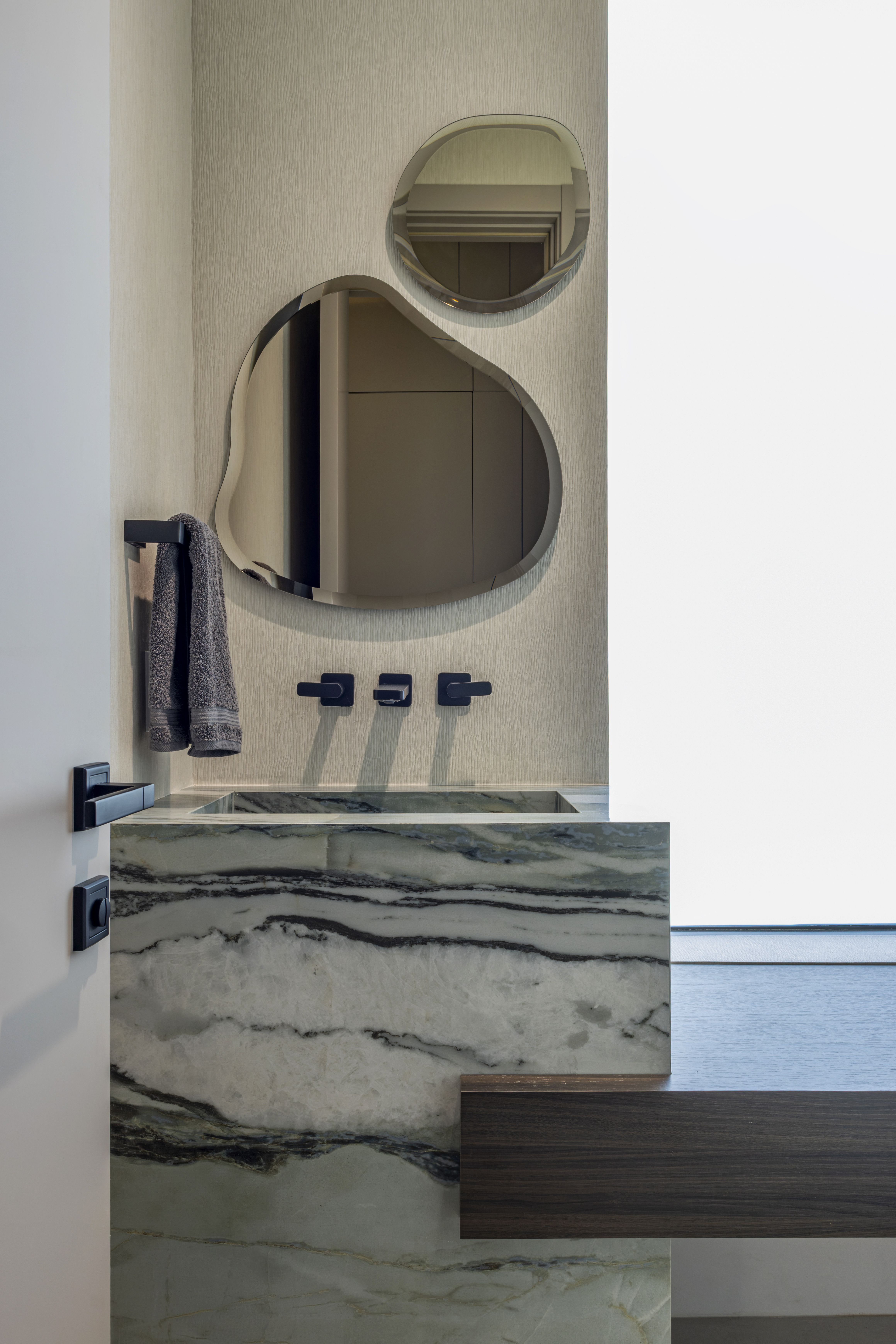 Powder bathroom — close-up of marble sink with sculptural mirrors