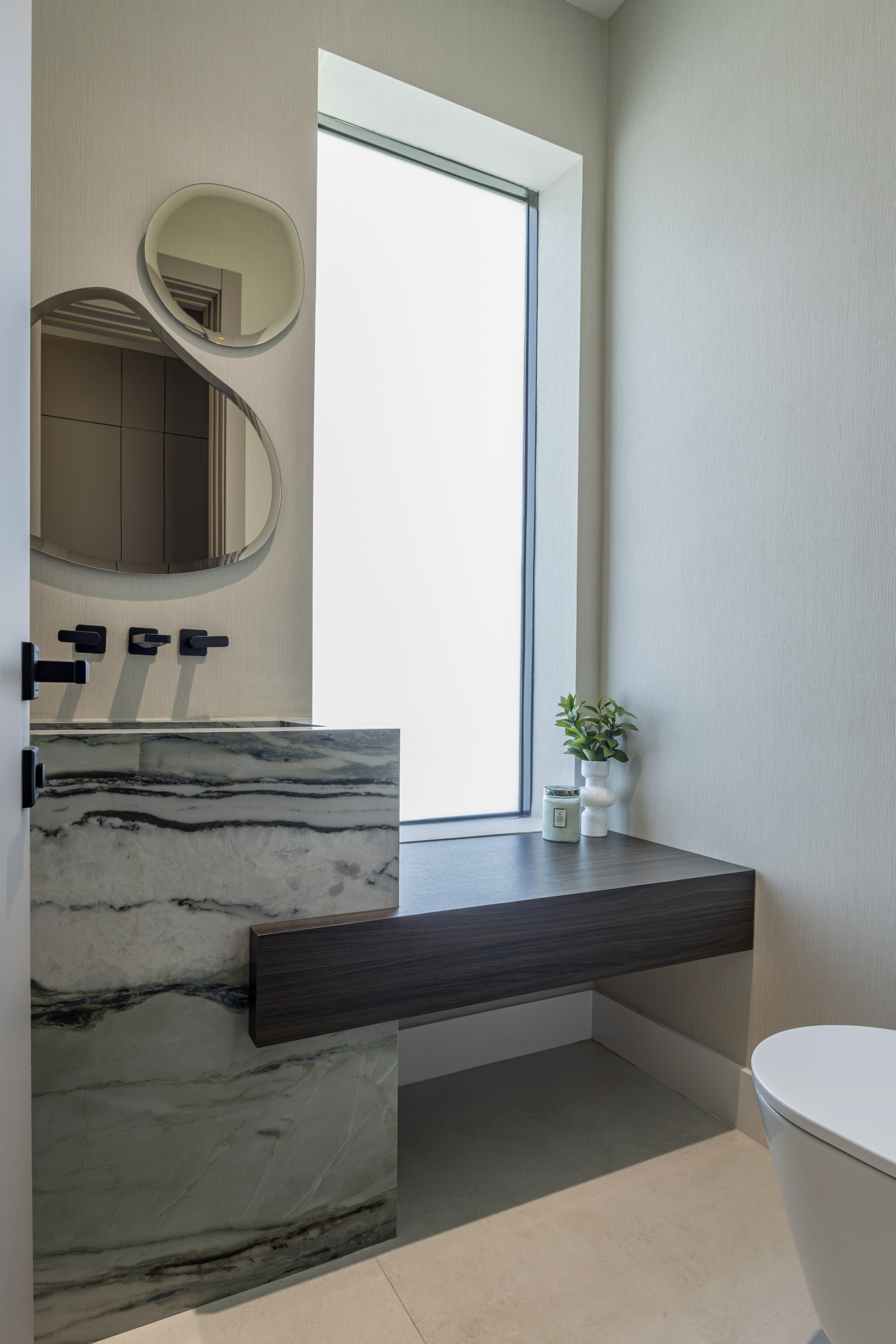 Powder bathroom — green marble sink with sculptural mirrors