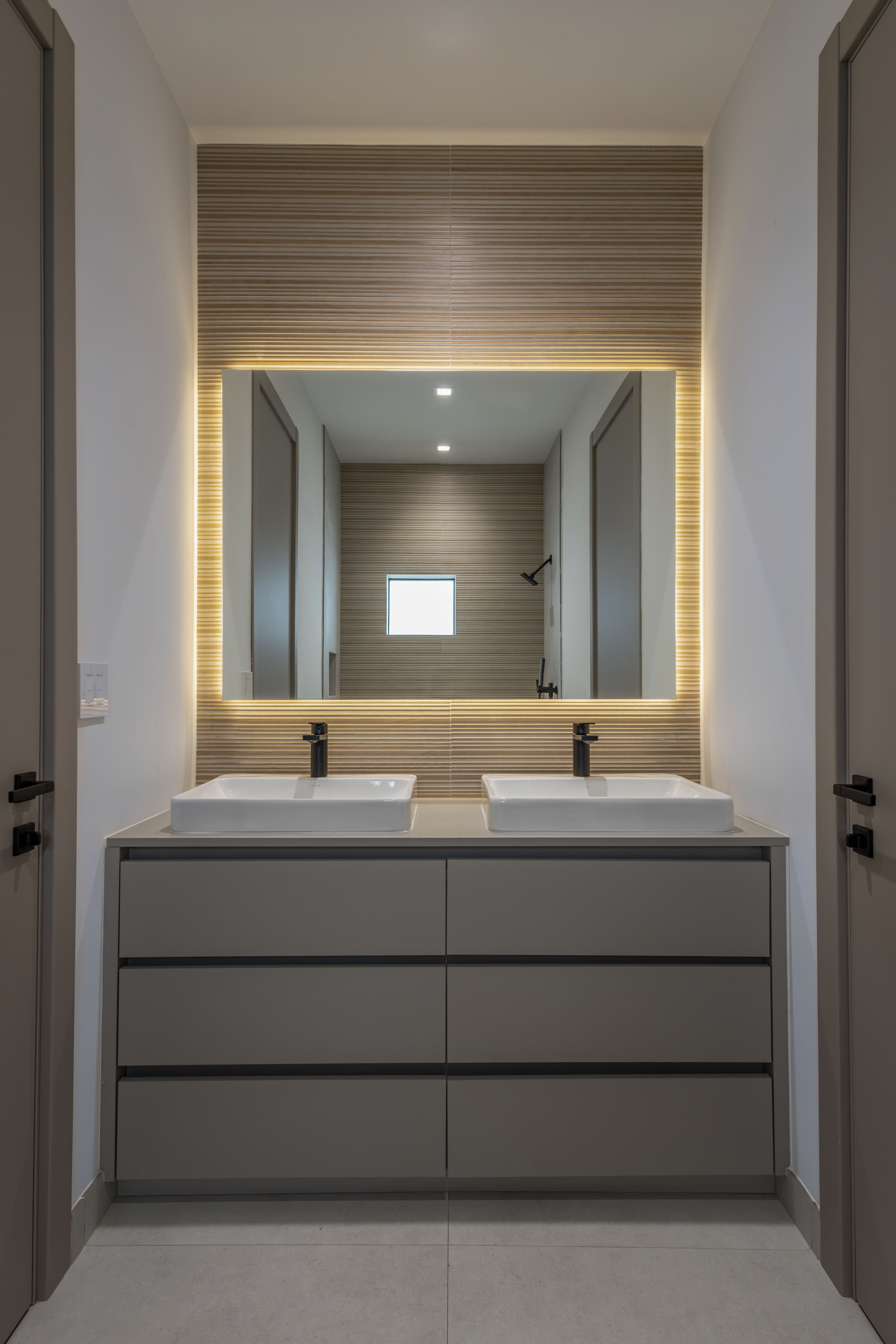 Bathroom — double vanity with backlit mirror and tile wall