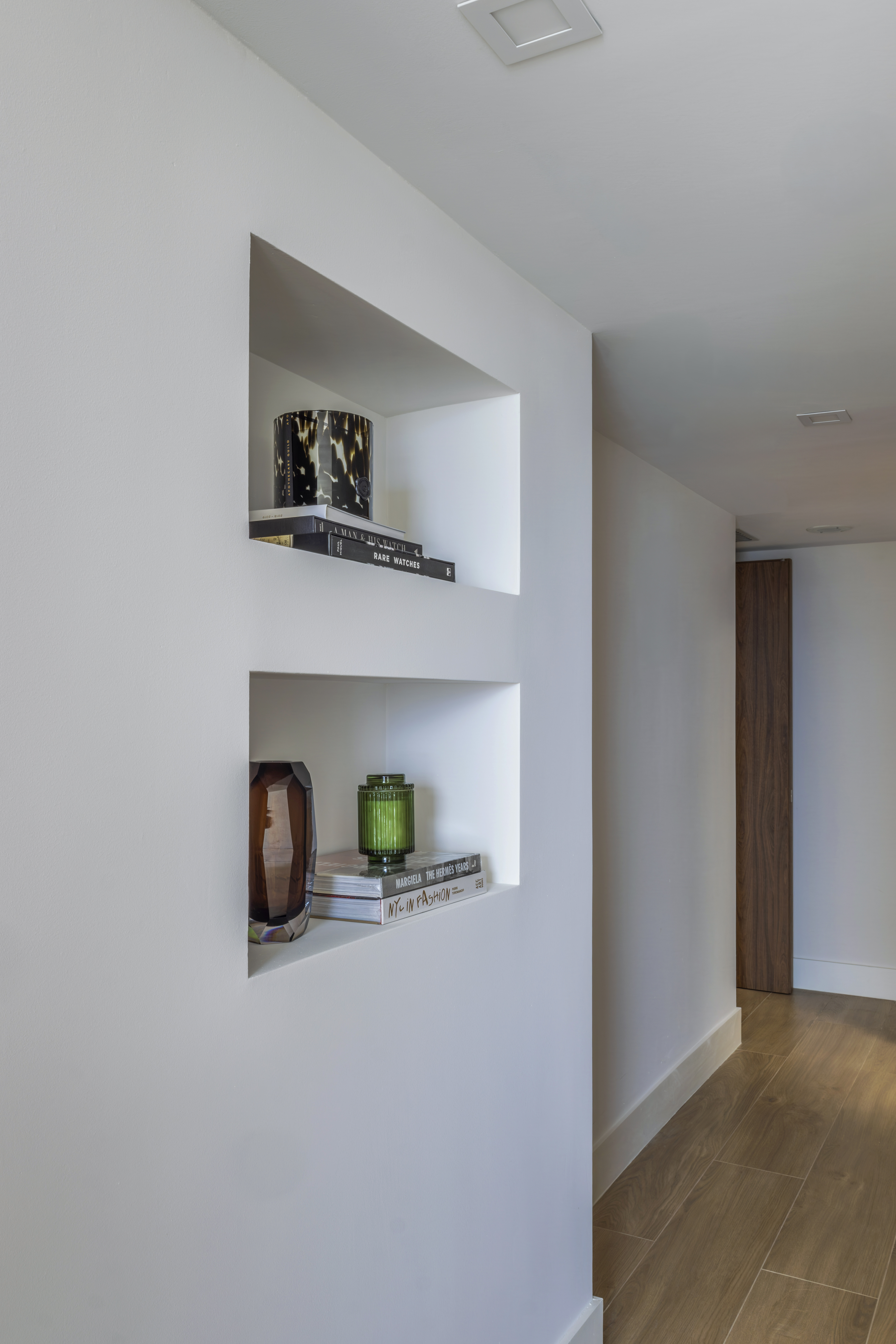 Hallway niche shelves styled with art books and decorative objects