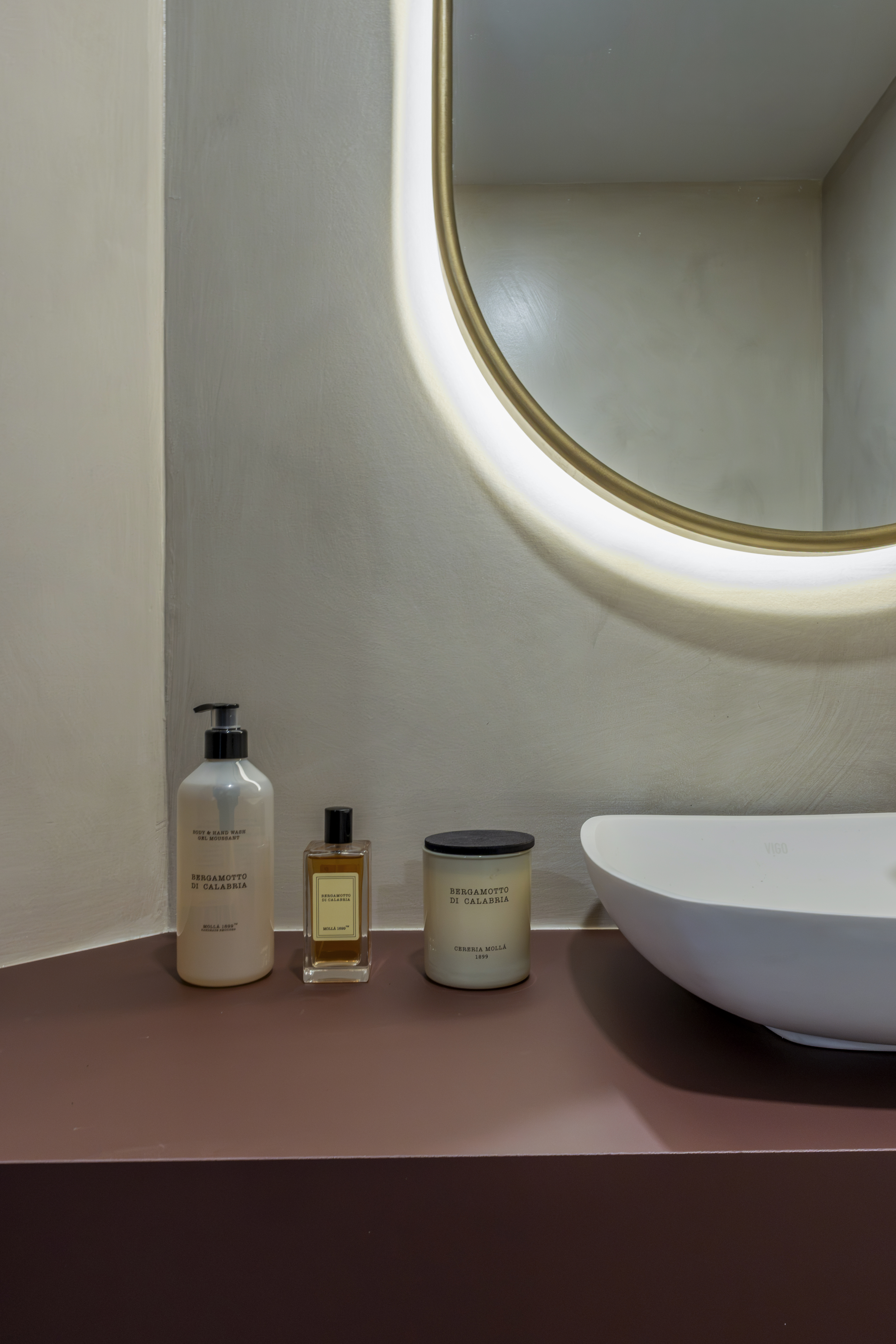 Powder room — counter with amenities and backlit mirror