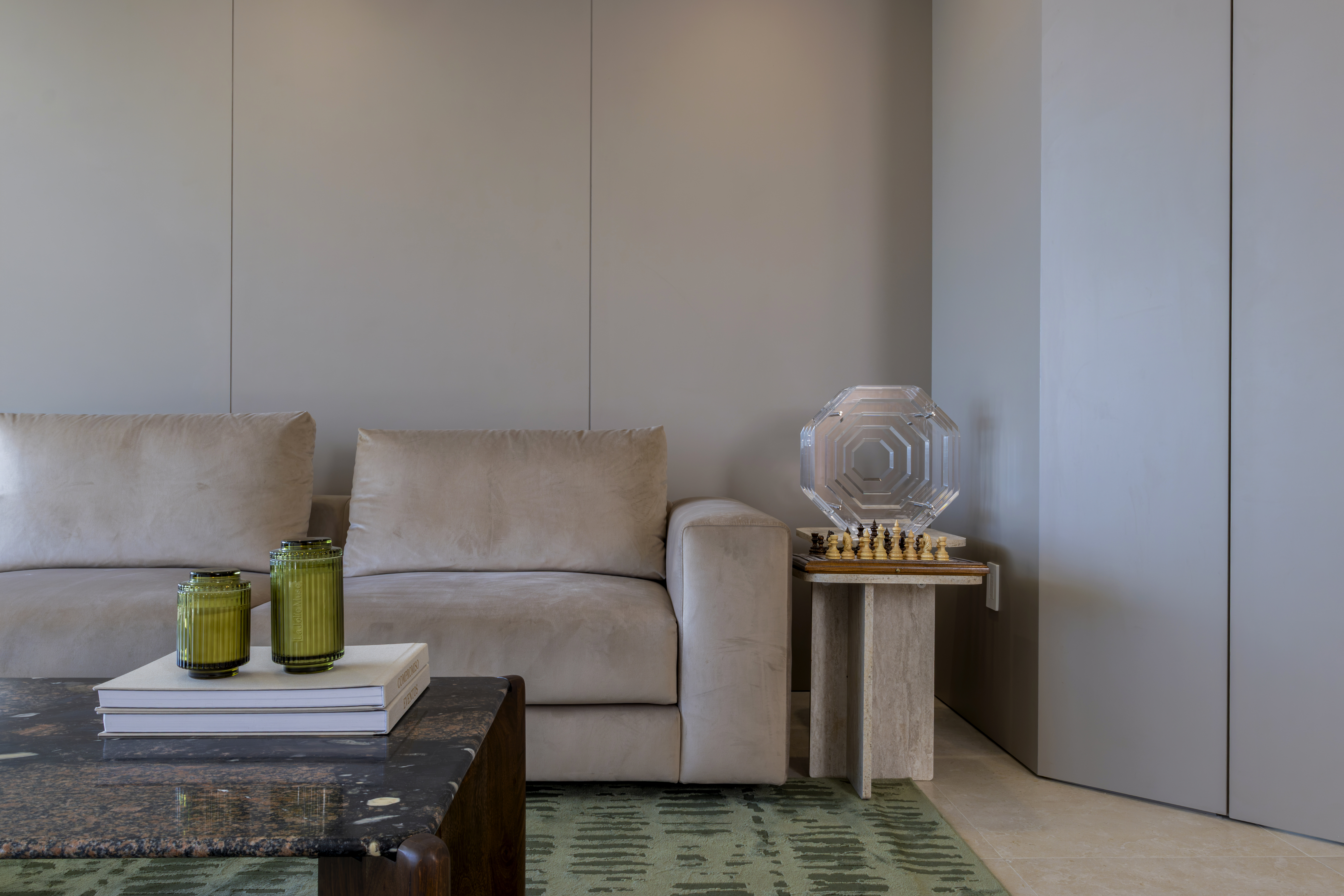 Sofa arm and travertine side table with chess set and crystal sculpture